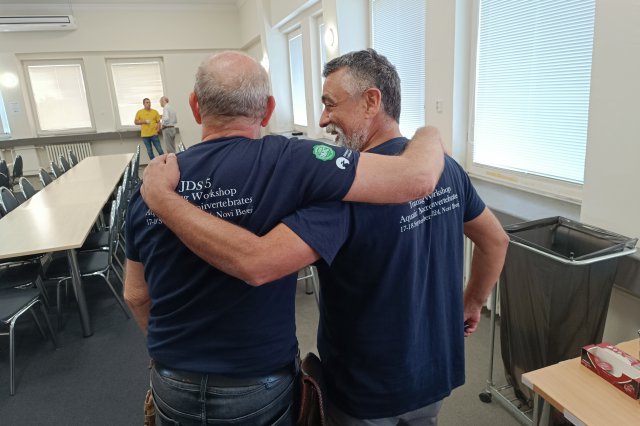 image of two men giving their back to the camera in a large meeting room 