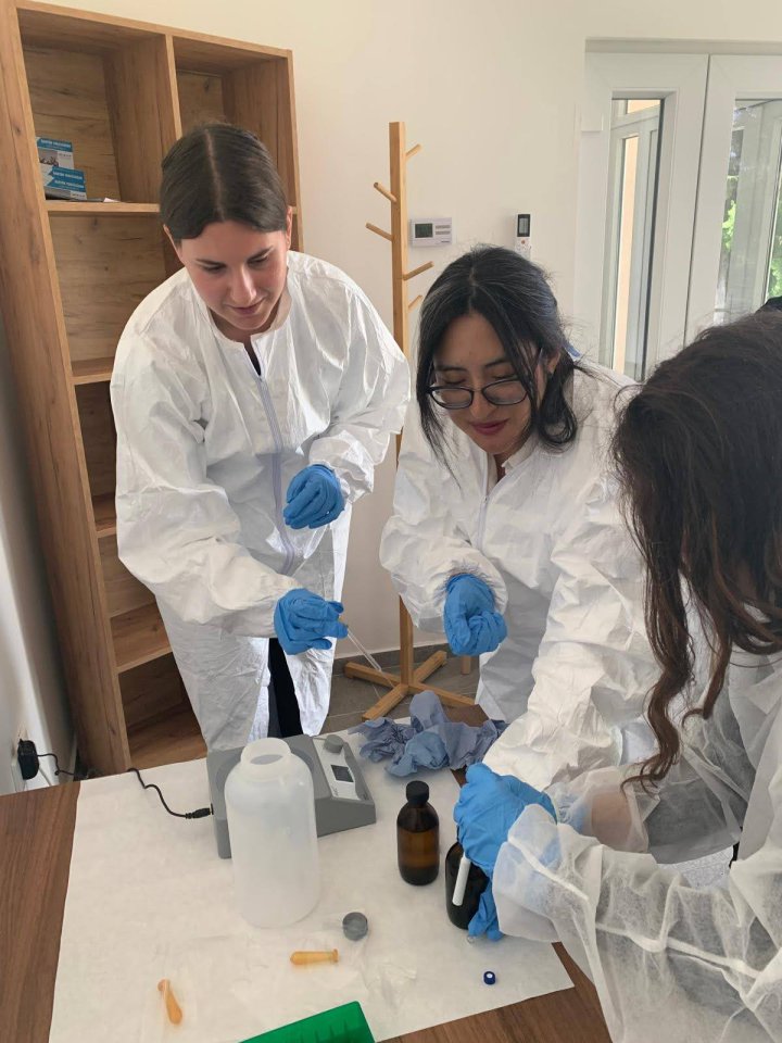 three women standing in a lab in white coats 